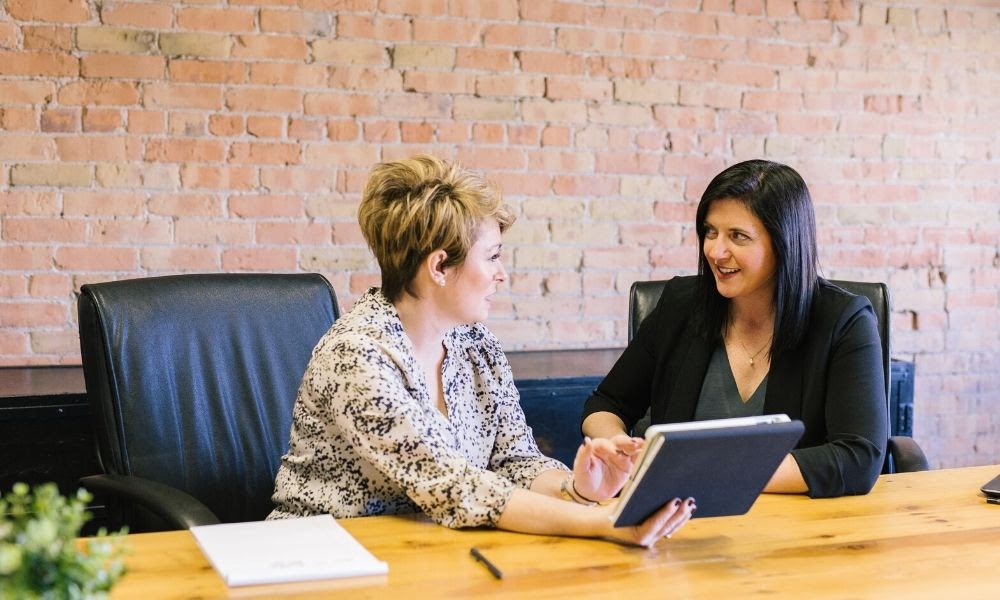 Looking over a proposal on a tablet, this image shows women at a business meeting.